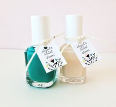 two bottles of nail polish sitting next to each other on a white surface with a tag hanging from the top