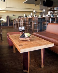 a wooden table with two glasses of wine on it in front of a brown leather couch