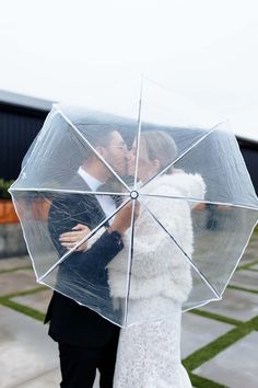 a bride and groom kissing under an umbrella