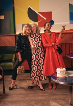 three women standing next to each other in front of a cake