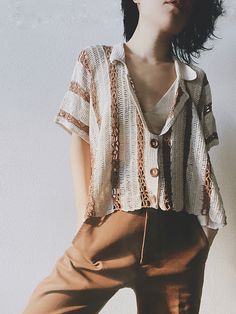 a woman standing in front of a white wall holding a brown purse and looking up at the sky