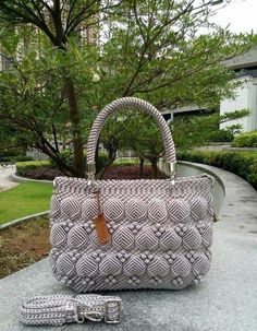 a handbag sitting on top of a cement slab next to a tree and bushes