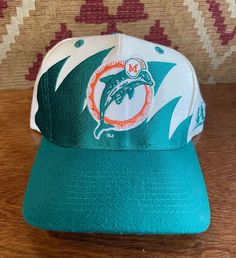 Bidding on a vintage 1990s Miami Dolphins shark tooth snapback in good condition Retro Curved Brim Hat For Sports Events, Retro Sports Cap, Retro Snapback Sports Hat, Retro Snapback Fitted Hat For Sports Events, Retro Snapback Visor Hat For Sports Events, Retro Fitted Hat With Curved Brim For Sports Events, Retro Curved Brim Fitted Hat For Sports Events, Retro Flat Brim Hat For Sports Events, Vintage Flat Brim Sports Hat