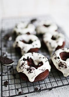 chocolate donuts with white icing and sprinkles on a cooling rack