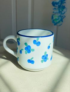 a blue and white coffee cup sitting on top of a table next to a wall