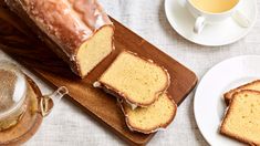 slices of pound cake sitting on top of a wooden cutting board next to two cups and saucers