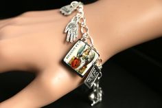 "A collection of silver plated and lead-free American pewter tarot and divination themed charms, along with a handmade \"La Giustizia\" (Justice) tarot card charm, have been dispersed around a shimmering silver plated bracelet chain in this handmade charm bracelet. This \"La Giustizia\" tarot charm bracelet is then completed with a lobster clasp and a 1/2 inch of chain at the end for adjustable sizing. The appearance of Justice in the tarot symbolizes fairness and balance. For a brief explanatio Tarot Jewelry, The Emperor Tarot, Dog Charm Bracelet, The Moon Tarot Card, Handmade Charm Bracelets, Metaphysical Jewelry, Relay For Life, Valentines Sale, Silver Plated Bracelet