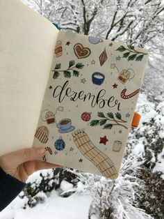 someone is holding an open book in front of snow covered trees and evergreens with the words november written on it