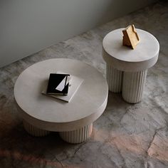 two white tables sitting on top of a marble floor