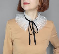 White Victorian ruffle tulle collar for parties, holidays, and themed events. A white neck ruff is a polka dot with a black velour ribbon.  The mobile accessory will instantly change the character of the image.  Even a simple dress turns into a piece of design art. The small detachable collar has unlimited possibilities. Could be a gift for her Size: 5.5 inches/ 14 cm A wonderful gift for women or female friends. The product is packed in an eco-cardboard box and is very beautifully presented. Visit our shop to see more detachable lace collars we offer: https://www.etsy.com/shop/MokushArt?section_id=31798144 Elegant Detachable Collar For Parties, Elegant Detachable Party Collar, Diy Clown Collar Ruffles, Clown Neck Ruffle, Elegant White Lace Collar, White Fitted Detachable Collar, Victorian Ruffle Collar, Tulle Collar, Clown Collar