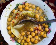 a white bowl filled with chickpeas next to a spoon