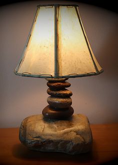 a lamp sitting on top of a rock covered table next to a white wall in a room