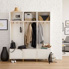 a room with a white brick wall and shelves filled with coats, jackets, purses and shoes