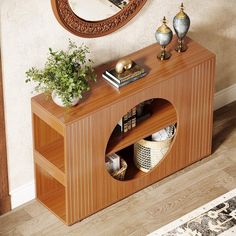 a wooden table with a mirror on the wall above it and plants in vases next to it