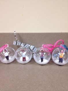 four glass ornaments with people in them and pink ribbon on the top one has a bow