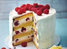 a cake with white frosting and raspberries on top is cut in half