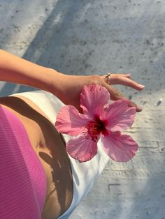 a woman holding a pink flower in her hand