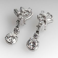 These gorgeous dangle style pierced earrings are each accented with five (5) prong set round brilliant cut diamonds and four (4) channel set baguette cut diamonds. The earrings measure 33.4mm in length and are finished with omega style backs. Platinum Diamond Earrings With Baguette Diamonds For Formal Events, Platinum Diamond Earrings With Baguette Diamonds For Formal Occasions, Platinum Diamond Earrings With Baguette Cut For Formal Occasions, Formal Platinum Diamond Earrings Baguette Cut, Formal Baguette Cut Diamond Earrings With Diamond Accents, Formal Baguette Cut Platinum Diamond Earrings, Formal Baguette Cut Diamond Earrings With Accents, Classic Clip-on Diamond Earrings, Classic Baguette Diamond Earrings For Formal Occasions