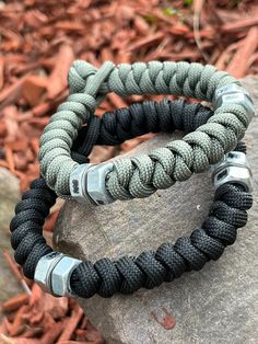 two black and gray bracelets sitting on top of a rock