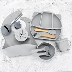 an assortment of grey children's dishes and utensils on a white surface