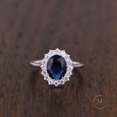 an oval shaped sapphire and diamond ring on a wooden table