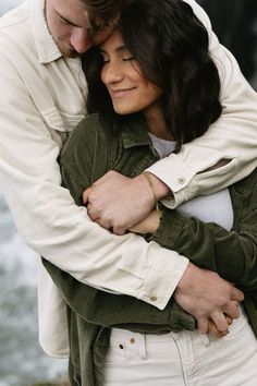 a man and woman embracing each other in front of water