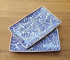 two blue and white plates sitting on top of a wooden table next to each other