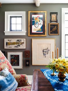 a living room filled with lots of pictures and flowers on the wall next to a coffee table