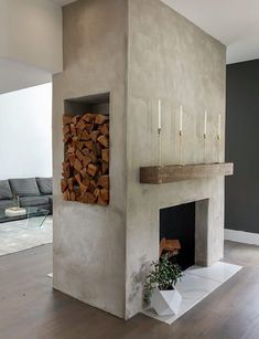 a living room with a fire place and wood stacked on top of each other in front of a couch