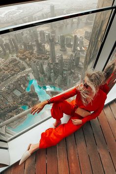 a woman sitting on top of a tall building looking out at the city from above