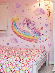 a child's bedroom decorated in pink, white and blue with a rainbow unicorn mural