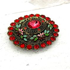 Authentic Vintage Little Nemo Oval Floral Brooch Pin Red Rhinestones Enamel SignedOutstanding colors and in excellent condition with minor enamel loss in tiny areas. All stones are present and original. Marked L/N on the reverse. A gorgeous rare brooch! This beautiful brooch measures 2 3/16 of an inch (55mm) by 1 15/16 of an inch (50mm). It is approximately 1/2 deep (13mm) deep at the center not including the pin stem.. Please see the photos for details and email us any questions.  Thank you for your interest! Gold Lion, Floral Brooch, Jewelry Pins, Stick Pins, Red Rhinestone, Brooch Pin, Vintage Jewelry, Silver Tone, Floral