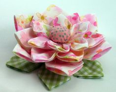 a pink flower with green leaves and polka dots on it's petals is sitting on a white surface