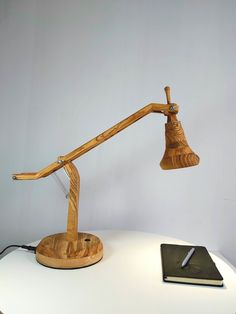 a desk lamp sitting on top of a white table next to a notebook and pen