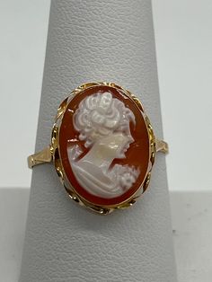 Sophisticated 14K conch shell cameo ring, with twisted frame. This ring portrays an elegant, handcrafted portrait of a woman wearing a flower brooch. This item was made in Italy from the APA collection. Original price $747. The cameo is 18 x 15 mm and weighs 1.9 grams. The ring is size 9. These earrings will arrive in a black pouch to gift yourself or someone else! Elegant Cameo Rings, Elegant Cameo Rings For Collectors, Black Pouch, Victorian Ring, Portrait Of A Woman, Cameo Ring, Victorian Rings, Conch Shell, Flower Brooch