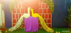 a decorated stage with flowers and a large white bird on it's back end