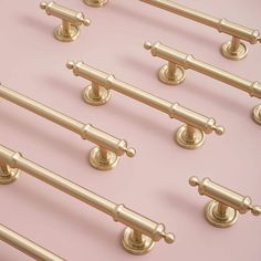 several brass handles and pulls on a pink background