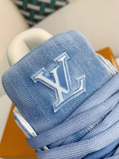 Step into iconic style with these LV Trainer-inspired sneakers reimagined in cool blue monogram denim. This contemporary take on a classic silhouette blends casual comfort with high-fashion appeal. The signature Louis Vuitton monogram adds a touch of understated luxury, while the clean lines and chunky sole create a versatile look that's perfect for everyday wear. Your order arrives in a branded shoe box, complete with dust bags, extra laces, socks, a care booklet, and a branded key holder. Designer High-top Sneakers With Logo Detail, Designer High-top Sneakers With Logo, Casual Blue High-top Sneakers With Logo, Blue Casual Sneakers With Embossed Logo, Designer High-top Sneakers With Embroidered Logo For Streetwear, Trendy Denim Blue Sneakers For Streetwear, Designer Blue High-top Sneakers, Designer Blue Sneakers For Spring, Fall Winter Jacket