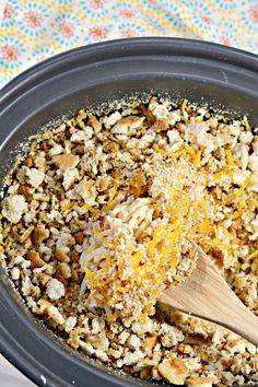 a wooden spoon mixing food in a crock pot on top of a table cloth