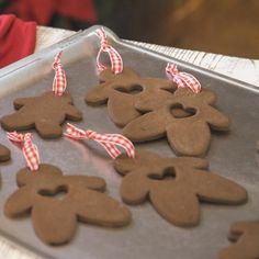 some cookies are shaped like people on a cookie sheet with red and white ribbon around them