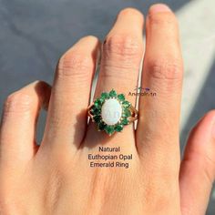 Natural Emerald Opal Ring For Women, Real Opal Ring For Women, Opal Cluster Ring With Emerald, White Opal Gemstone Ring, Opal Halo Ring Gift Vintage & Feminine White Opal & Emerald Floral Ring- petite & beautiful. A delightful & feminine 14ct gold Plated over 925 Silver white opal and emerald cluster ring, featuring a cabochon oval opal surrounded by a halo of round cut emeralds in this traditionally classic style. A raised claw setting completes the style of this elegant ring. 𝐒𝐩𝐞𝐜𝐢𝐟𝐢𝐜? White Gemstone Rings For May Birthstone, White Emerald Ring Jewelry, Emerald And Opal Ring, Round Emerald Ring With Natural Stones For Anniversary, Oval Cabochon Emerald Wedding Jewelry, Wedding Emerald Jewelry Oval Cabochon, Wedding Emerald Oval Cabochon Jewelry, Vintage Feminine, White Opal Ring