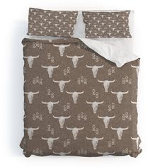 a bed with a brown and white bull pattern on the comforter, along with two pillows