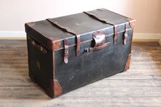 an old suitcase is sitting on the floor in front of a wall and wooden floors