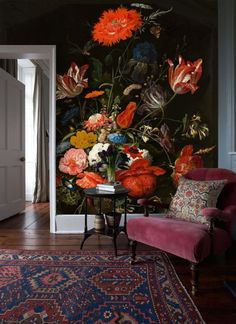 a living room with a rug, chair and wallpaper that has flowers on it