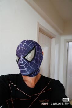 a person wearing a spider man mask in a room