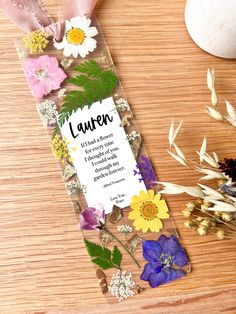 a bookmark with flowers on it sitting next to some dried plants