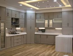 a large kitchen with wooden floors and white counter tops on the ceiling is lit by recessed lights