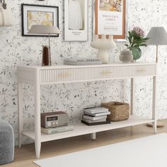 a white console table sitting in front of a wall covered with pictures and framed photos