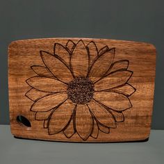 a wooden cutting board with a large flower on it's side and a black dot in the center