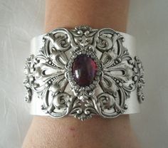 "This beautiful silver plated cuff bracelet has a silver plated floral design and a glass dragon's breath fire opal setting with rhinestone accents. 2\" wide. Adjustable." Elegant Silver Cuff Bracelet With Jewels, Ornate Silver Jeweled Bracelets, Ornate Silver Bracelet With Jewels, Ornate Silver Bracelets With Jewels, Victorian Silver Bracelets With Jewels, Handmade Victorian Silver Cuff Bracelet, Victorian Style Handmade Silver Cuff Bracelet, Ornate Antique Silver Cuff Bracelet For Weddings, Victorian Silver Cuff Bracelet With Intricate Design